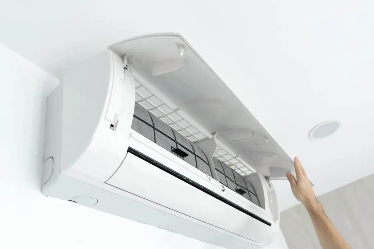 Hand opening the cover of a wall-mounted ductless air conditioner